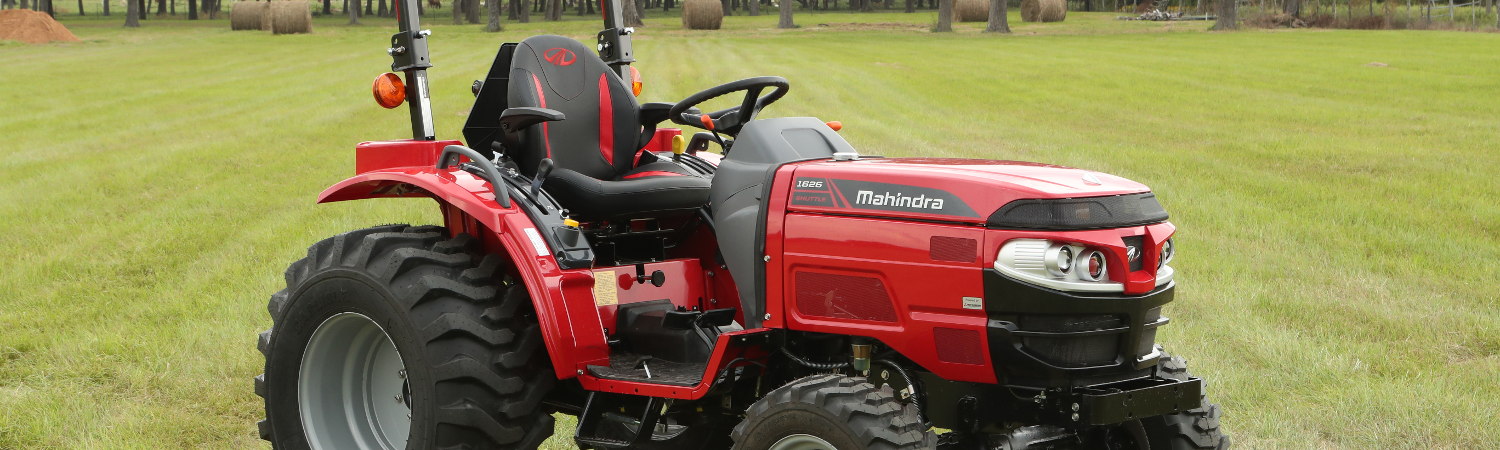 Mahindra® 1626S tractor parked on a green lawn on a farm